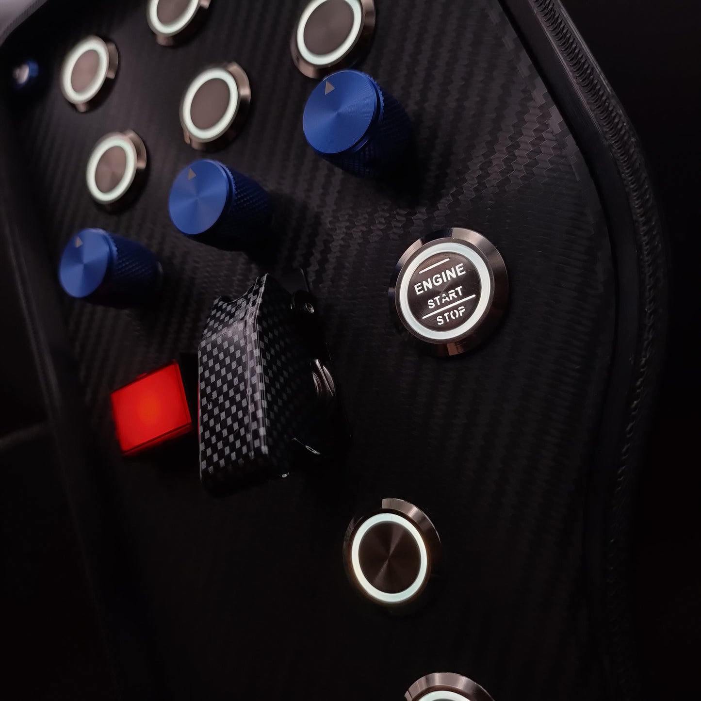 Close-up of blue machined aluminium rotary encoders and white LED Engine Start button on the GT Blue.
