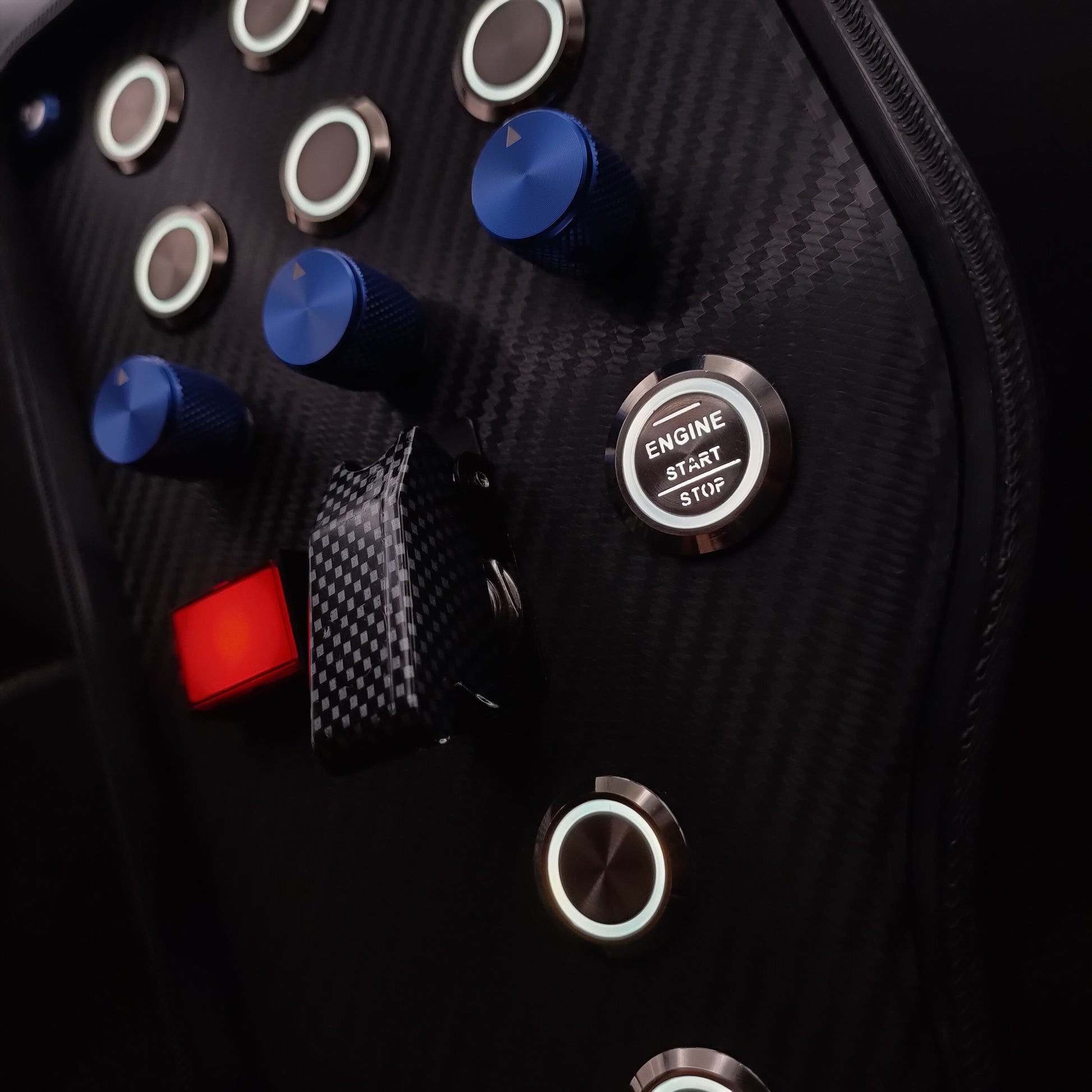 Close-up of blue machined aluminium rotary encoders and white LED Engine Start button on the GT Blue.
