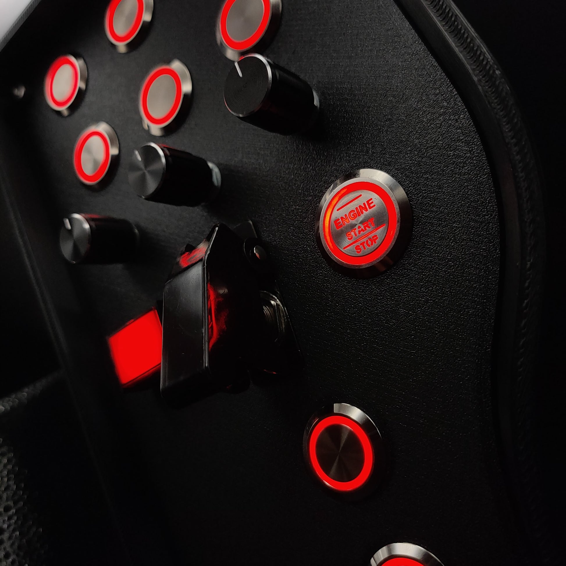 Close-up shot of the red LED illuminated buttons and the black ignition toggle switch set against a matte textured background.