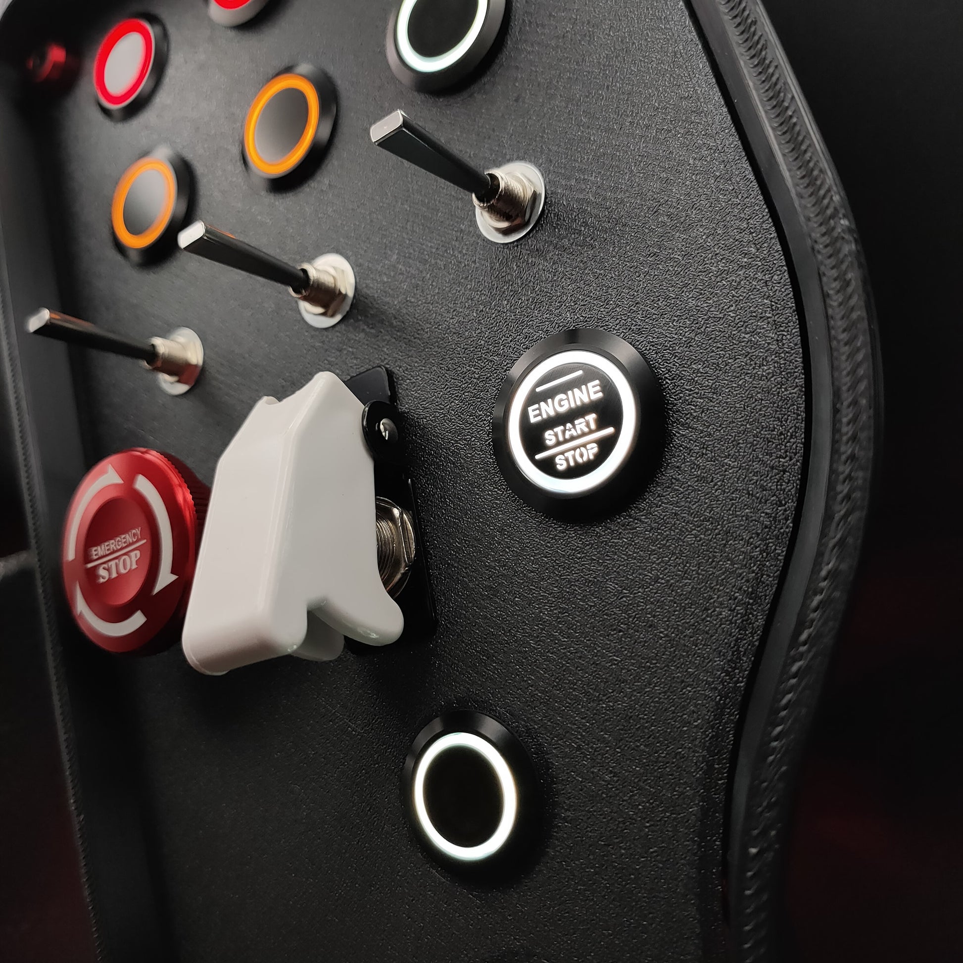 Close-up of the red aluminium emergency stop button and industrial 3-way momentary toggle switches.