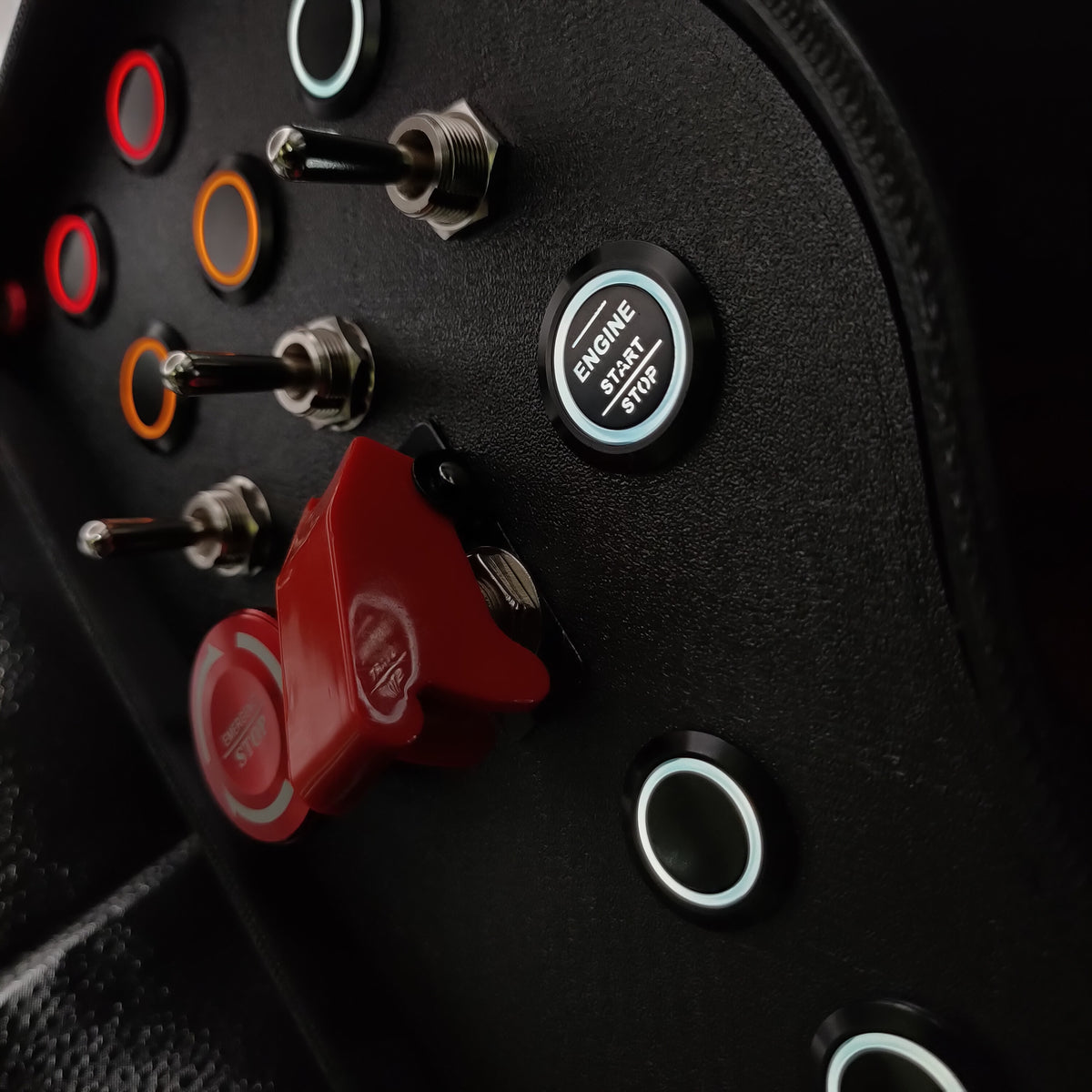 Close-up of the red aluminium emergency stop button and industrial 3-way momentary toggle switches.
