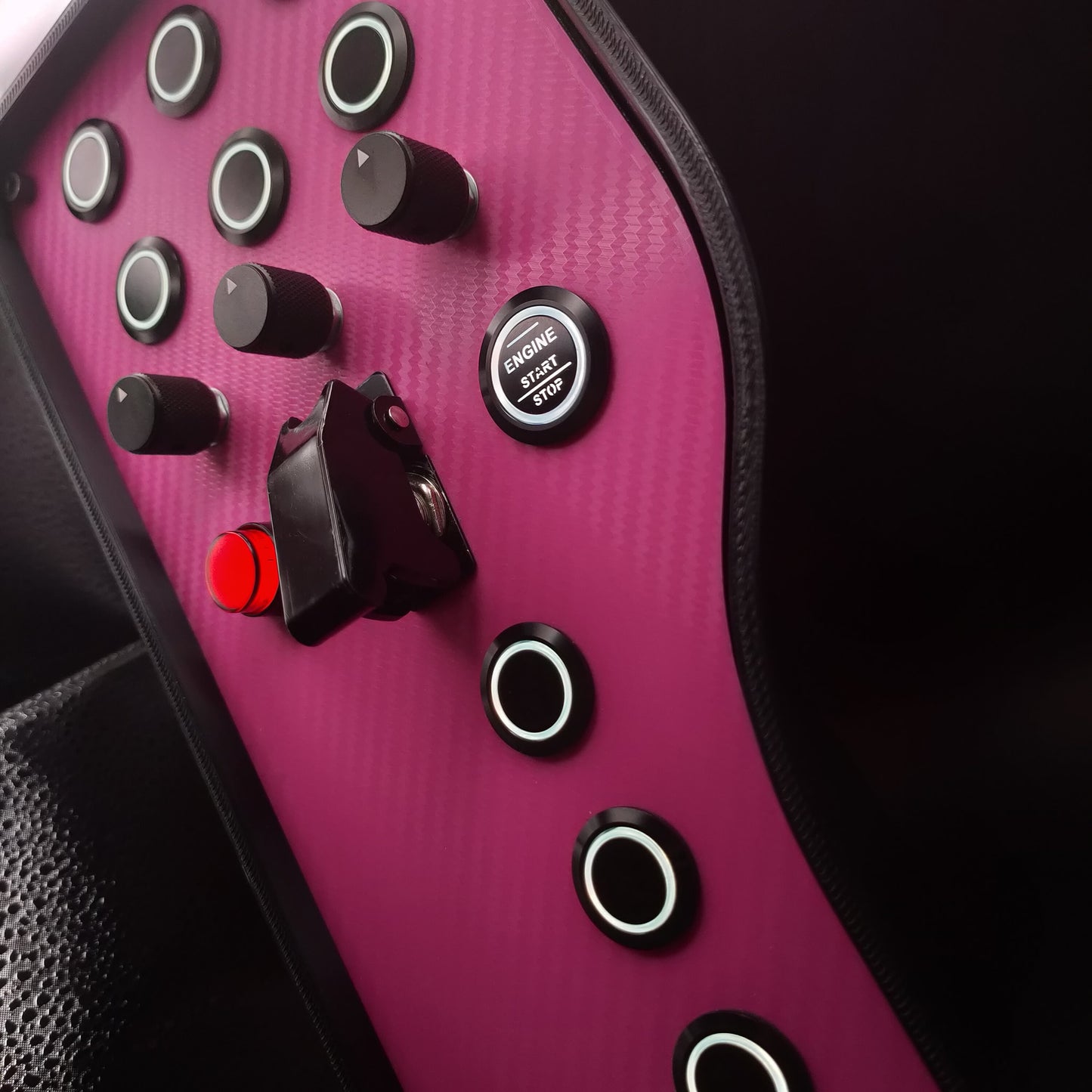Close-up of black machined aluminium rotary encoders and engine start button on the Pink Edition button box.