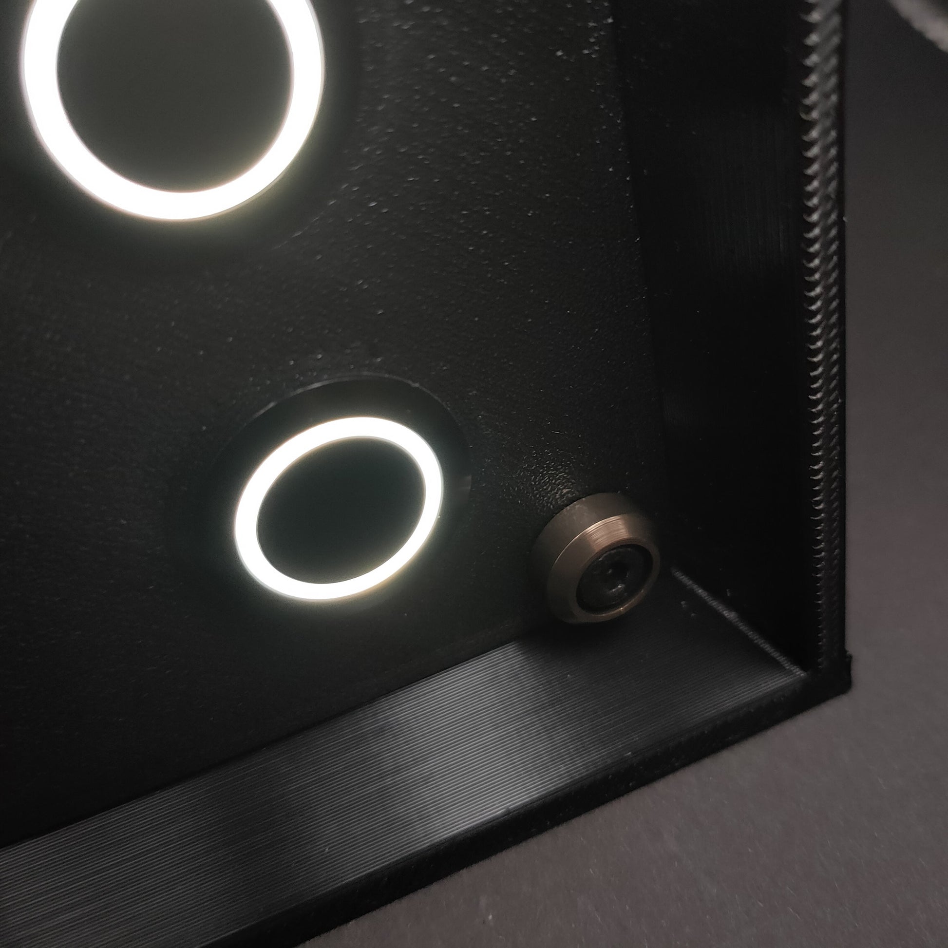 Detail shot of black anodised aluminium bolt trim and black brushed aluminium buttons on matte black.