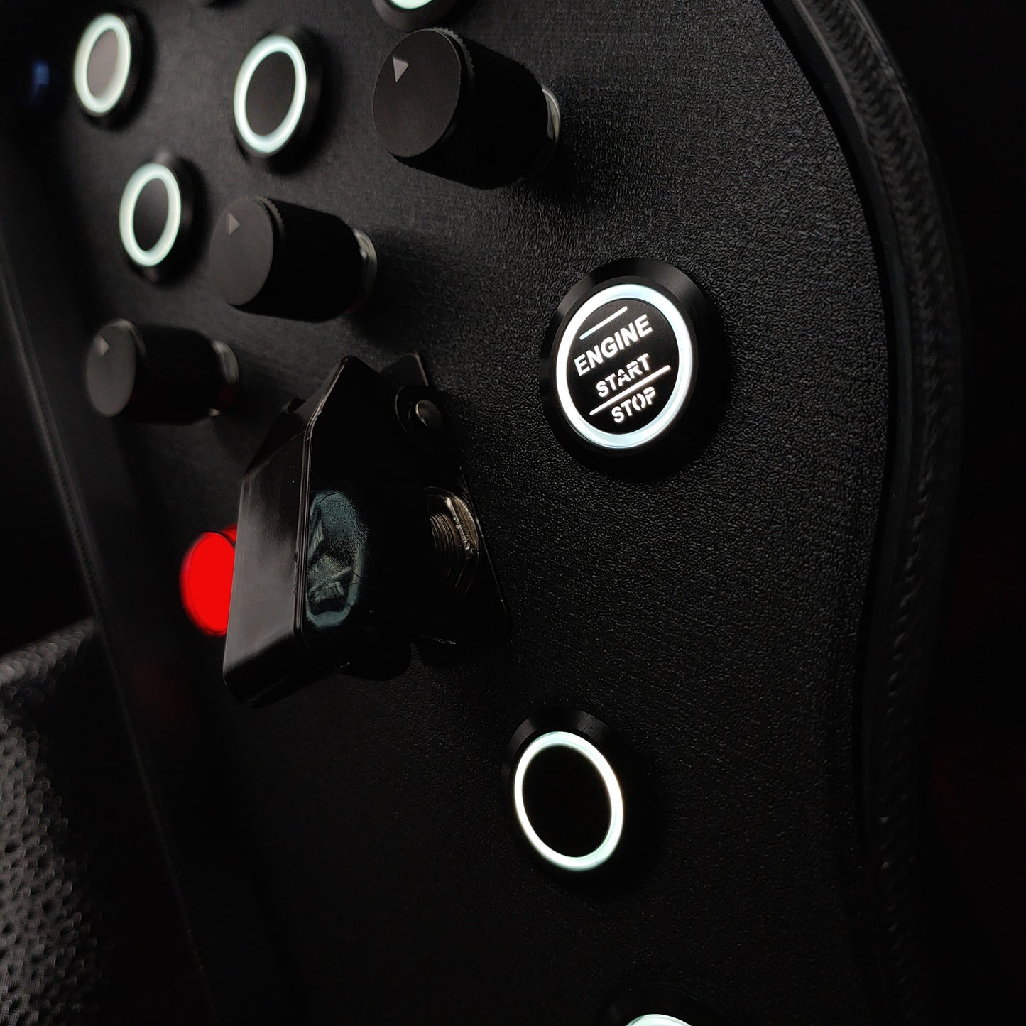 Close-up of black machined aluminium rotary encoders and white LED start button on Blue Edition.