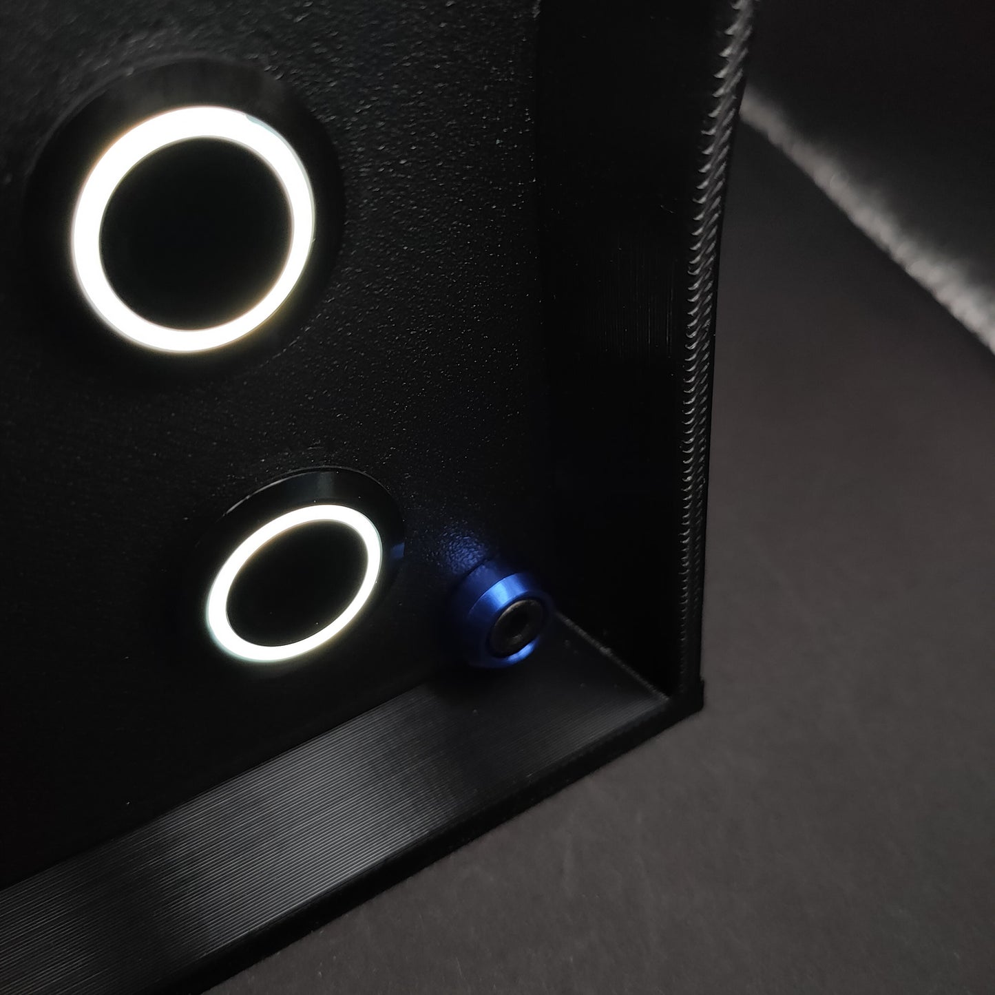 Detail shot of premium blue anodised aluminium bolt trim on a matte black sim racing button box.