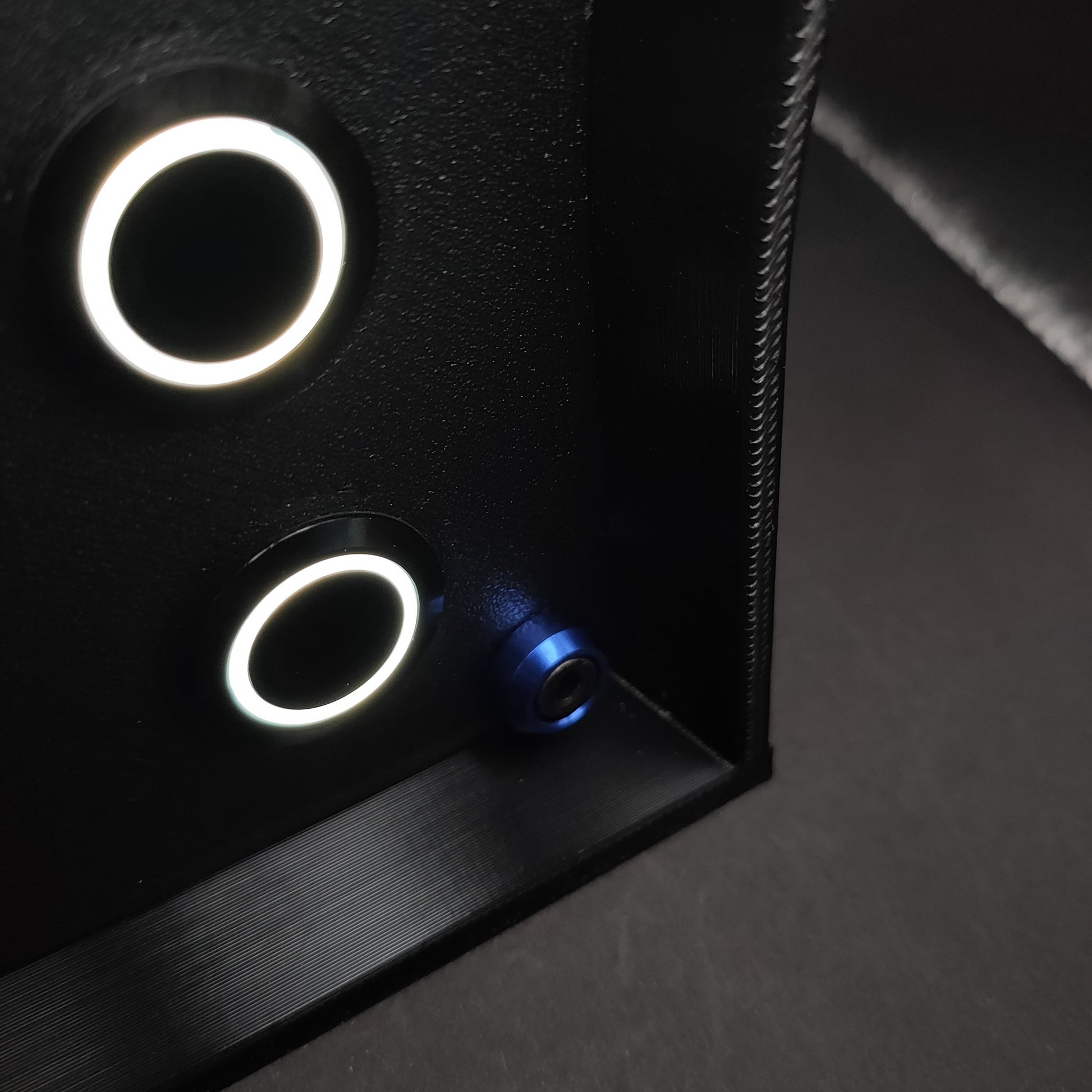 Detail shot of premium blue anodised aluminium bolt trim on a matte black sim racing button box.