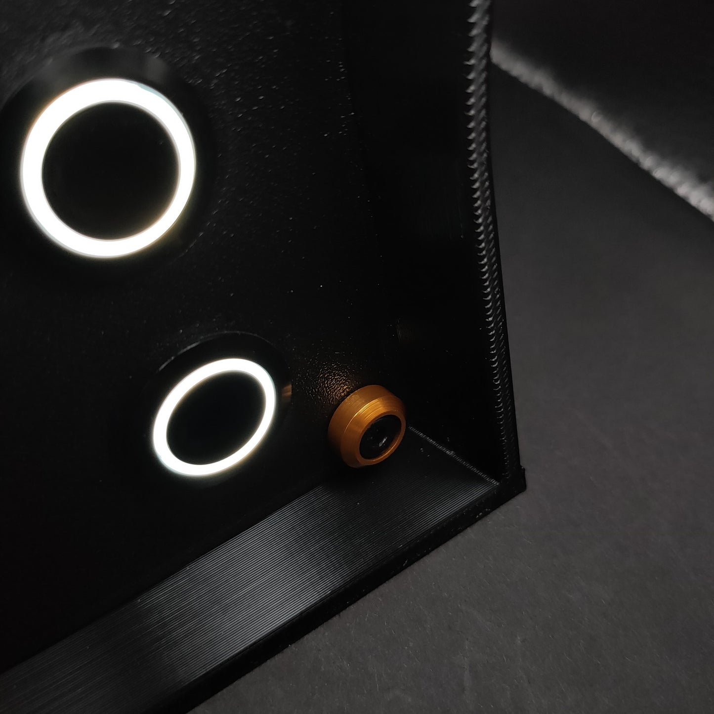 Detail shot of premium gold anodised aluminium bolt trim on a matte black sim racing button box.