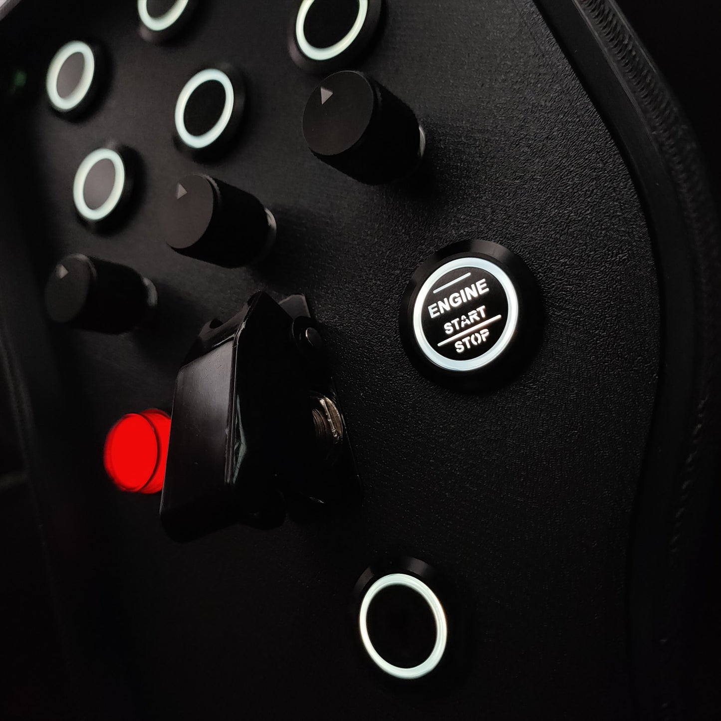 Close-up of black machined aluminium rotary encoders and white LED start button on Green Edition.