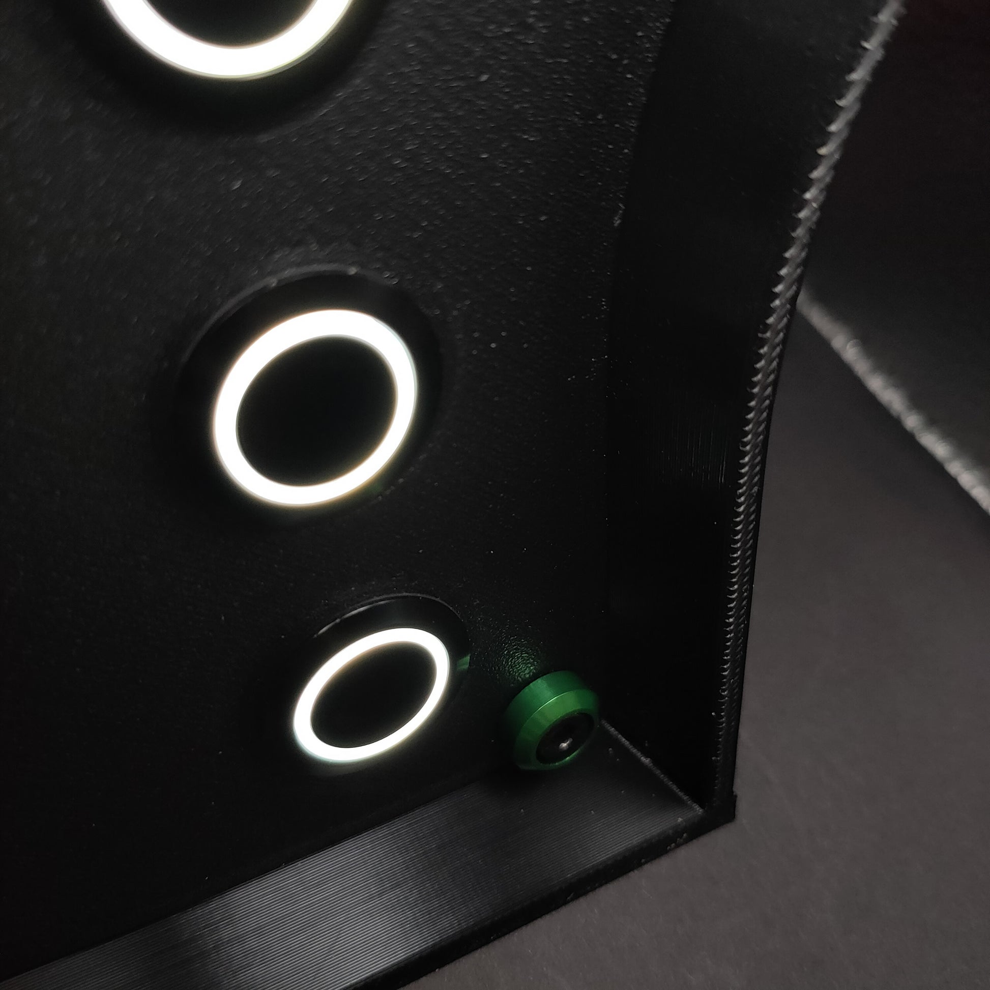 Detail shot of vibrant green anodised aluminium bolt trim on a matte black sim racing button box.