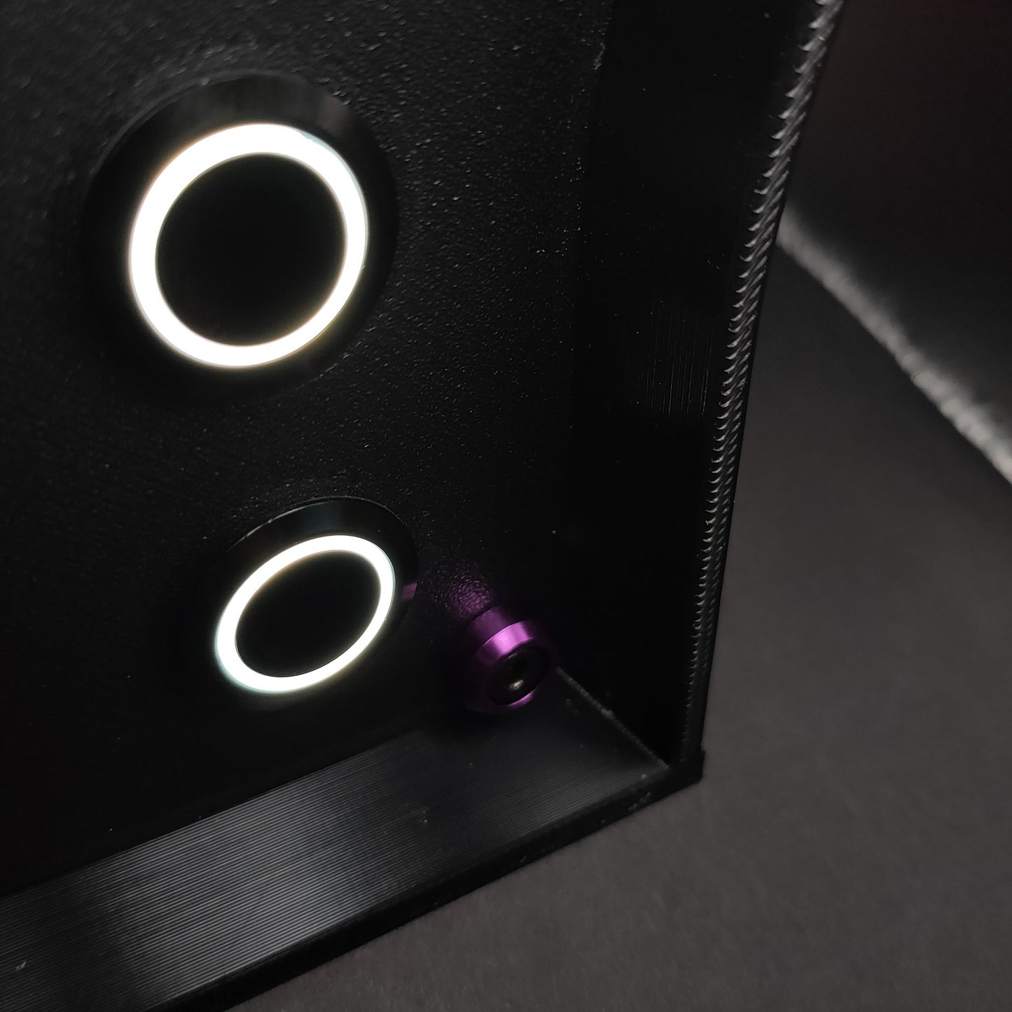 Detail shot of premium purple anodised aluminium bolt trim on a matte black sim racing button box.