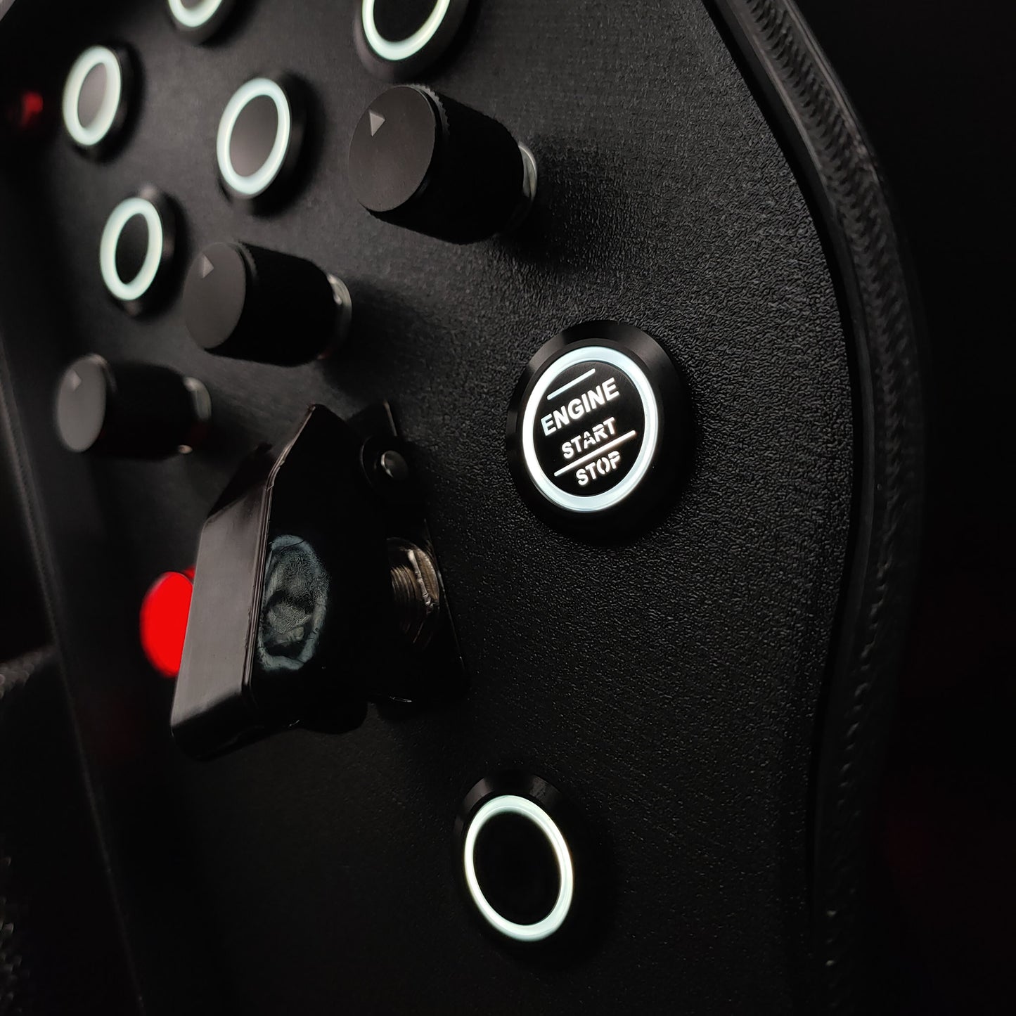 Close-up of black machined aluminium rotary encoders and white LED start button on Red Edition.